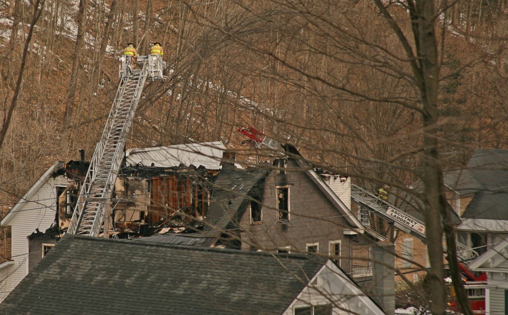 Len Emery photo Fire crews attend to the burned-out shell of an apartment building in Springfield Monday. 